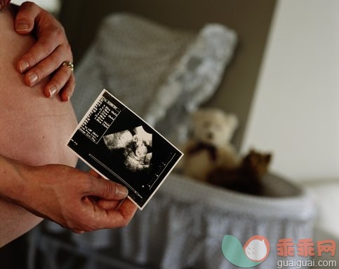 健康保健,人生大事,摄影,婴儿用品,婴儿床_200144016-001_Pregnant woman standing next to bassinet, holding ultrasound photo_创意图片_Getty Images China